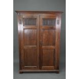 A 17th century style oak wardrobe, the twin doors with part linenfold moulded panels, on block feet,