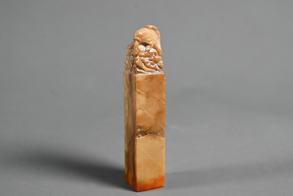 A Chinese butterscotch coloured soapstone seal carved with a carp and wave finial, four character