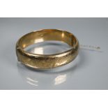 A 9ct yellow gold oval half hinged bangle, with foliate engraved decoration to front, concealed