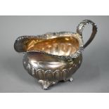 A Regency silver cream jug, the gadrooned rim chased with shells, oak leaves and acorns, floral