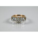An aquamarine half eternity ring set with seven baguette cut pale aquamarines in yellow metal