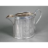 A small Victorian silver cream jug of fluted oval design with chased foliage and scroll handle,