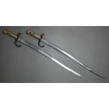 Two 19th century French sabre bayonets, with 57.5 cm curving blades, one marked St Etienne 1869, the