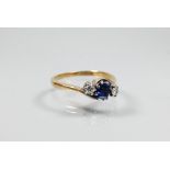 A sapphire and diamond three stone ring in crossover setting, the square blue sapphire flanked by