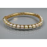 A yellow metal pearl-set bangle, the pierced open grill core set with thirty-one cultured pearls