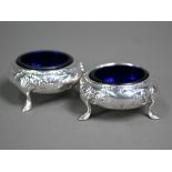 A pair of Victorian circular silver open salts with engraved floral decoration, on hoof feet,