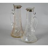 Matched pair of Edwardian cut glass claret jugs with flared bases and silver collars and covers with