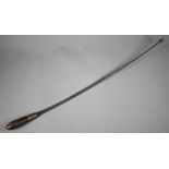 An antique weapon, the 60 cm curved steel blade with barbed finial, on brass-mounted rosewood