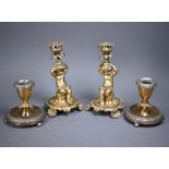 A pair of Rococo style gilt bronze candlesticks, modelled as seated cherubs raised on organic form