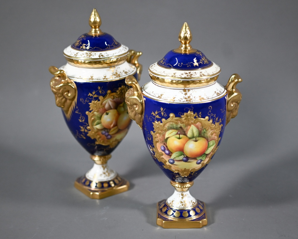 A pair of boxed Coalport blue-ground urns and covers, the reserves painted with fruit still lifes