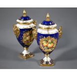 A pair of boxed Coalport blue-ground urns and covers, the reserves painted with fruit still lifes