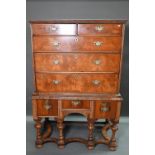 A George III feather-banded walnut chest on stand, composed of two short over three long graduated