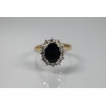 An traditional oval cluster ring with dark blue sapphire surrounded by twelve claw set diamonds,