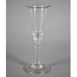 A Georgian drinking glass, the elongated bowl with flared rim, on baluster stem with folded foot-