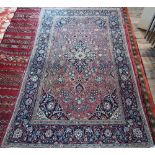 An antique Persian Kashan rug, the central medallion and floral vines on dull maroon ground, 204 x