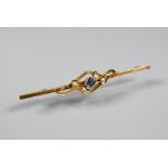 An Edwardian bar brooch set with four small seed pearls and blue stone, yellow metal set stamped