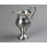 An Edwardian silver baluster cream jug in the Georgian manner, with scroll handle and circular