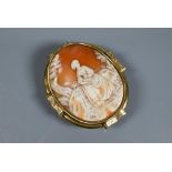 A large Victorian carved shell cameo brooch featuring maiden seated in a landscape, yellow metal