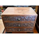 A small three drawer collector's chest with foliate carved front and brass handles, 35 cm wide x