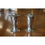 A pair of Edwardian planished silver pepperettes in the Art Nouveau taste, of tapering form with