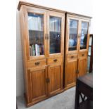 A pair of golden oak bookcase cabinets with glazed doors enclosing adjustable shelving and