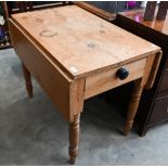 A waxed pine drop-leaf side table with end drawer having ebonised handle, raised on turned supports,