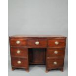 A Victorian mahogany bowfront kneehole desk, with six drawers and recessed cupboard, raised on