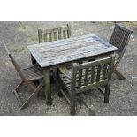 A weathered stained teak patio set, comprising dining table, 122 x 74 x 69 cm h, pair of armchairs