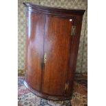 An antique oak barrel front hanging corner cupboard with two doors, 105 cm h