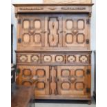 A large golden oak court cupboard with three drawers and geometric panelled cupboard doors in the