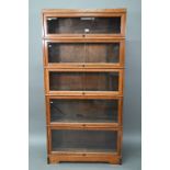 Fandson, London, a five tier golden oak five section library bookcase, with glazed-in hinge-over