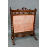 A Victorian mahogany framed fire screen with polychrome armorial device to the crest rail, over a