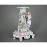 A German porcelain pedestal, modelled with a shy maiden playing hide and seek with Cupid around a