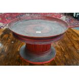An early 20th century Burmese red and black lacquer circular tray on attached stick-spindle stand (