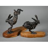 Two brown bronze sculptures of hares, one running, one leaping, both on yew wood bases, 15 cm and 13