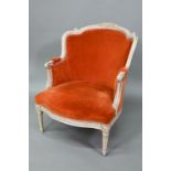 An old French salon armchair with orange upholstery, the moulded frame with distressed parcel gilt