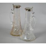 A matched pair of Edwardian cut glass claret jugs with flared bases and silver collars and covers