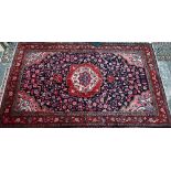 A North West Persian Sarouk carpet, the red ground centred by a blue ground medallion and floral