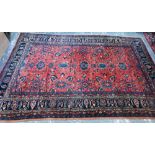 A large Persian Sarouk carpet, the dark salmon-red ground with stylised floral design within blue