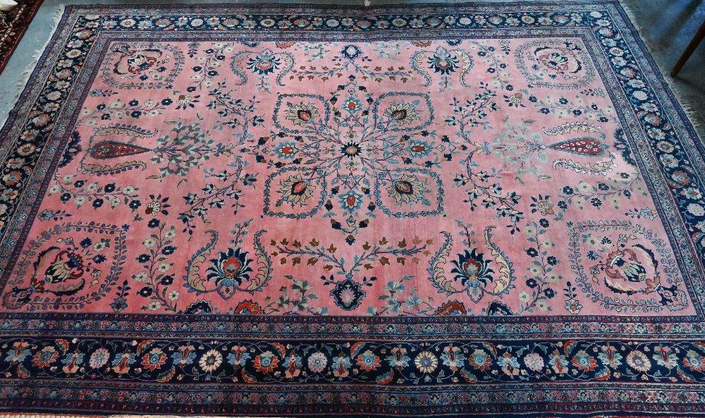 A large old pink ground Persian Sarouk carpet with navy blue floral border, 470 cm x 322 cm