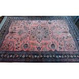 A large old pink ground Persian Sarouk carpet with navy blue floral border, 470 cm x 322 cm