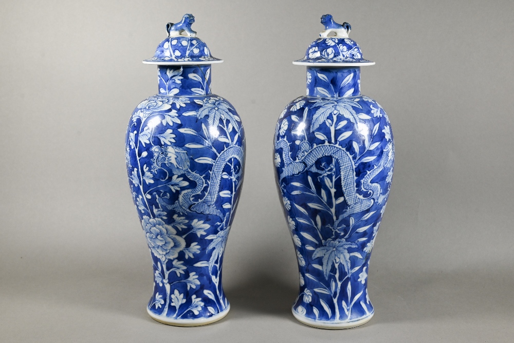 A pair of 19th century Chinese blue and white vases with domed covers surmounted by guardian lion