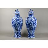 A pair of 19th century Chinese blue and white vases with domed covers surmounted by guardian lion