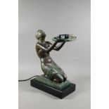 An Art Deco Verdigris patinated bronze table lamp, modelled as a kneeling woman with bowl of
