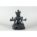 A Nepalese bronze figure of the three-faced Buddhist goddess Vasudhara, seated in royal ease