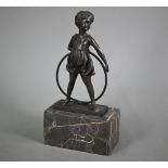 After Ferdinand Preis, a reproduction brown bronze figure of a girl with hoop, signed to base, 26 cm