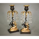 A pair of Empire period bronze and gilt candlesticks, with palm-fronds suspended with glass bead