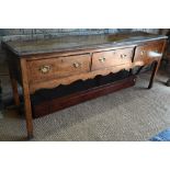 A late 17th century oak three drawer low dresser, raised on square section legs, later brass