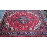 A Persian Heriz carpet, the red ground with stylised floral design centred by a blue medallion,