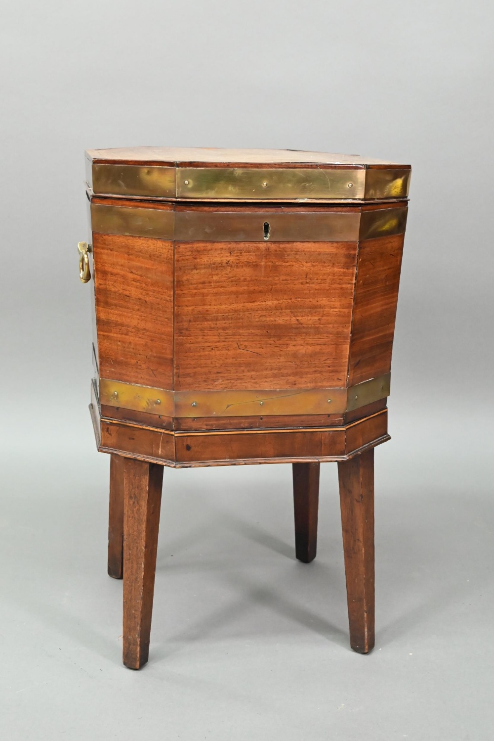 A George III brass bound mahogany wine cooler of octagonal form, with internal zinc liner, raised on